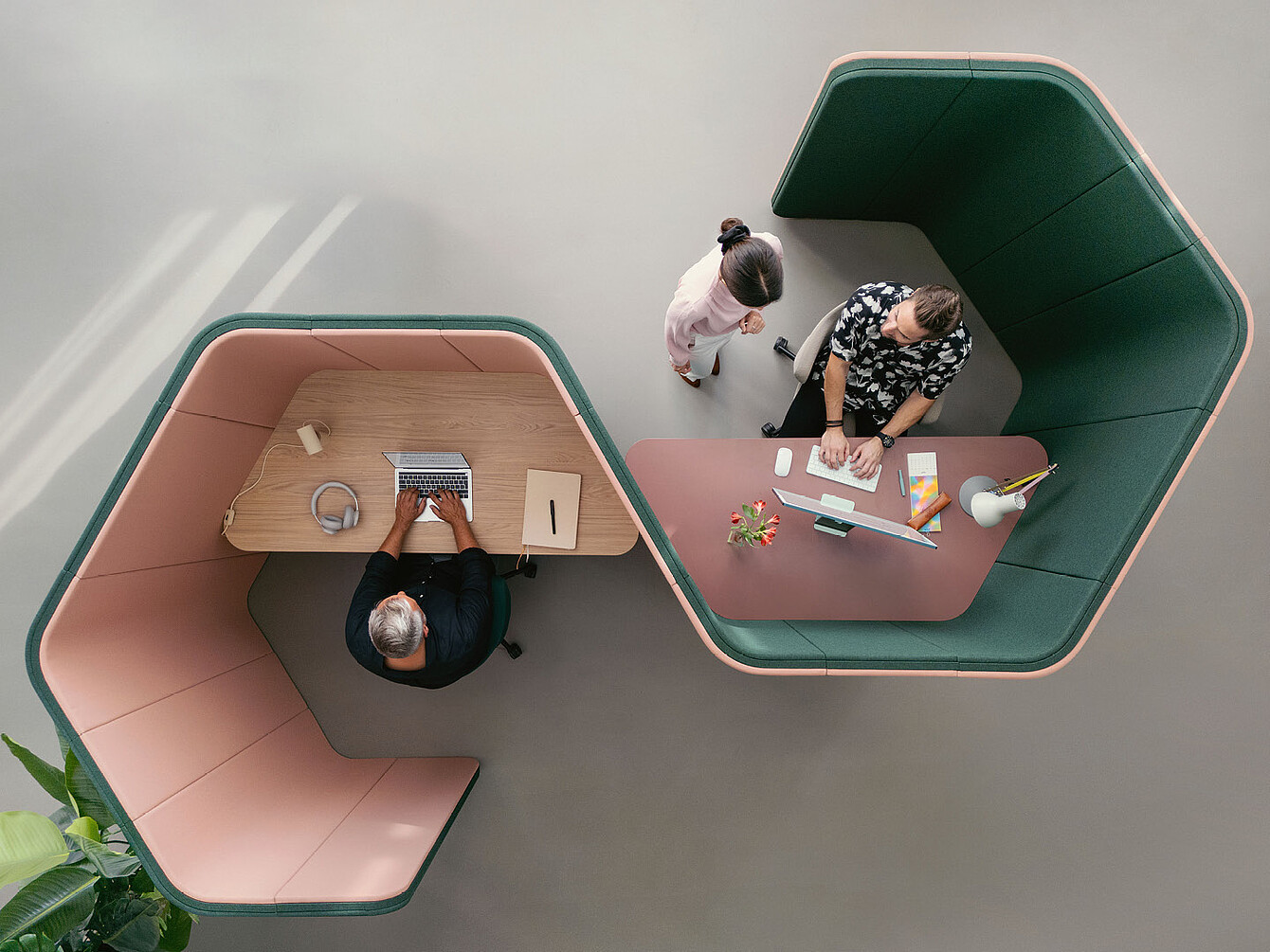 Deux personnes travaillant dans des modules de bureau hexagonaux adjacents se:hive, l’une utilisant un ordinateur portable et l’autre un ordinateur de bureau, vue de dessus