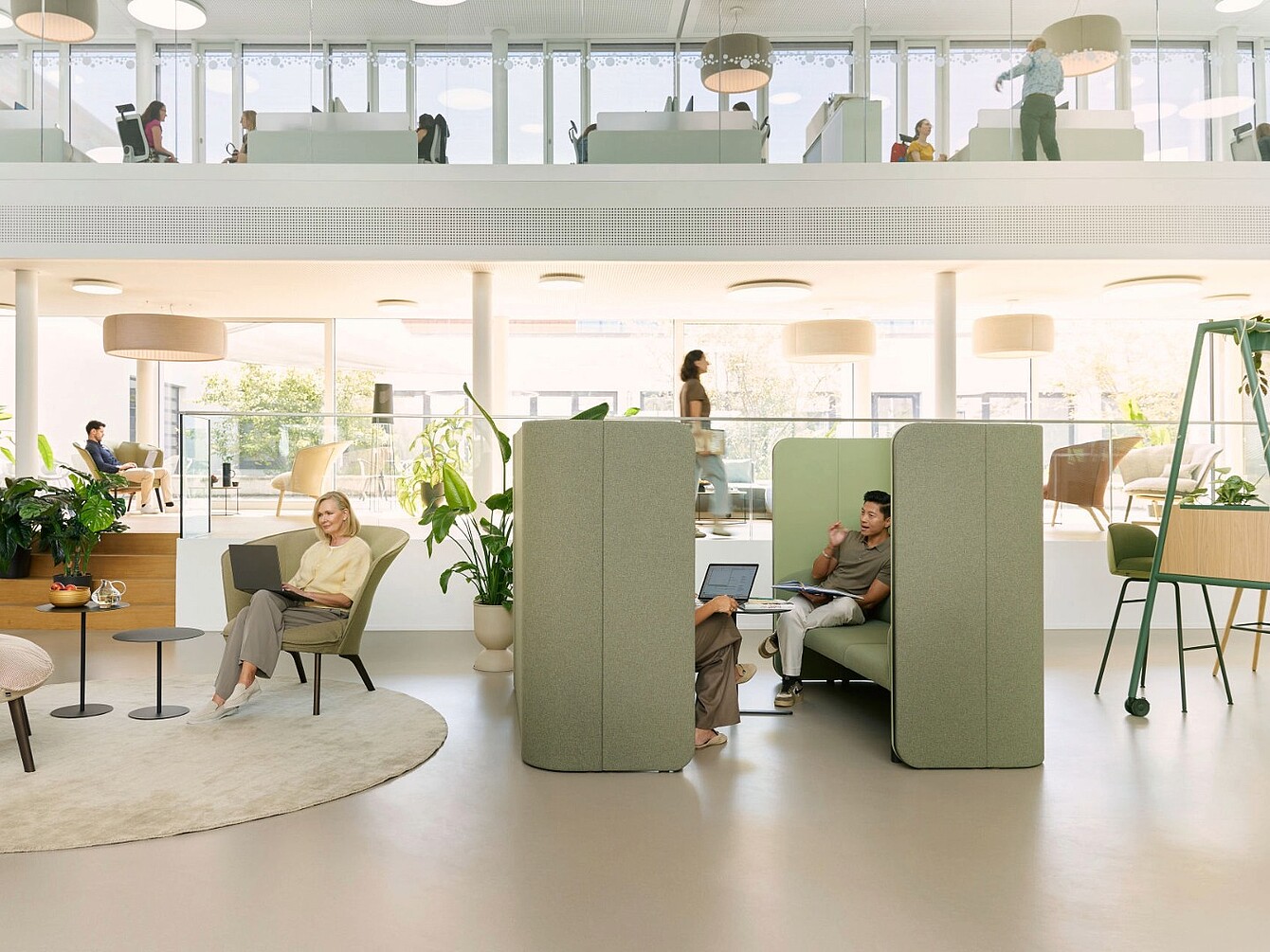 Open office space with modular se:hive creating semi-enclosed retreat areas, surrounded by chairs, tables, plants, and people working or walking.