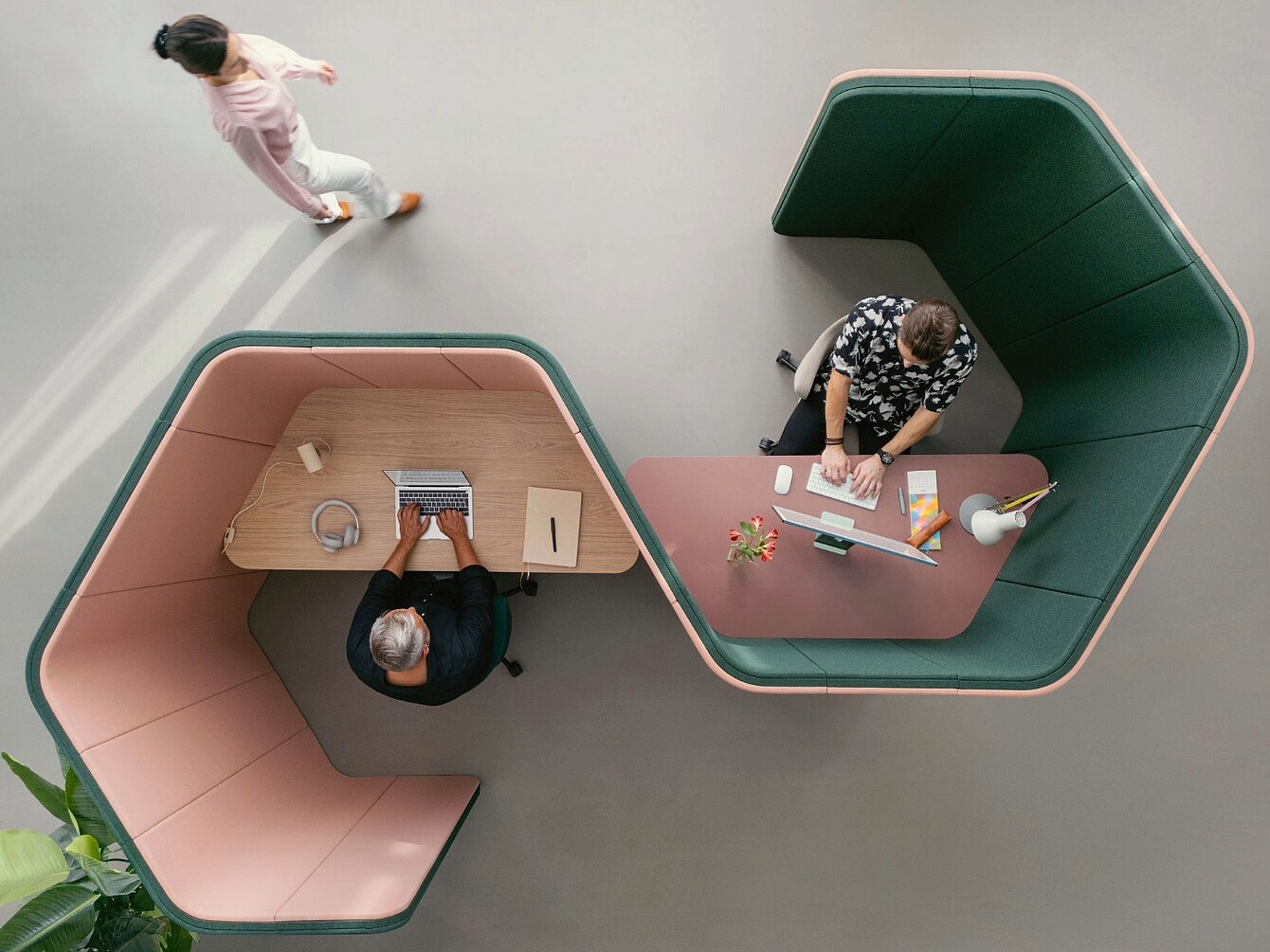 Due postazioni di lavoro esagonali se:hive con pareti imbottite alte, una con una persona che utilizza un laptop e cuffie, l’altra con una persona che lavora su un computer desktop, vista dall’alto