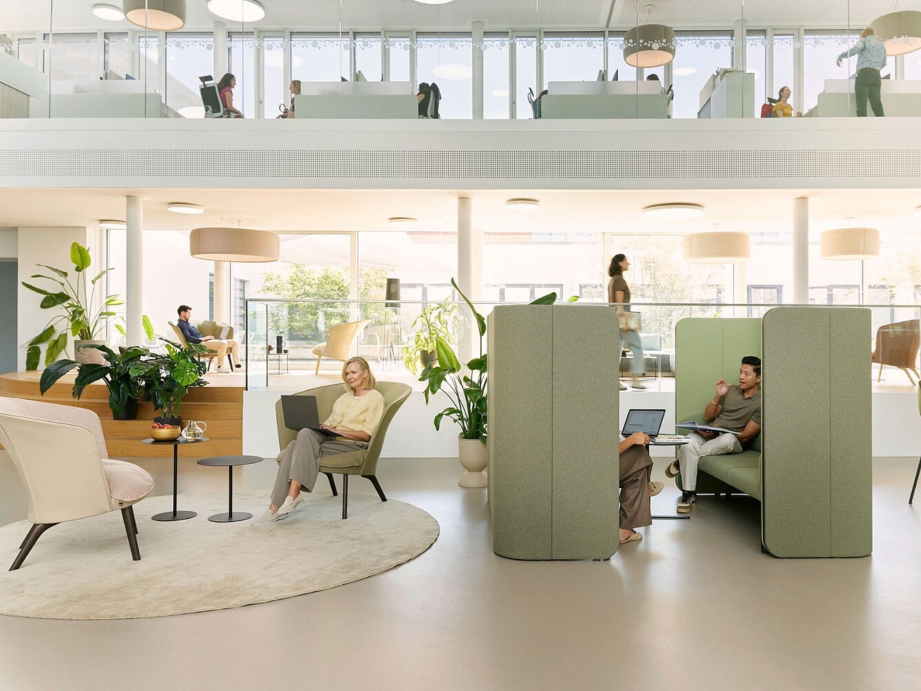 Espace de bureau moderne avec des postes de travail ouverts, des cabines acoustiques et de la lumière naturelle provenant de grandes fenêtres