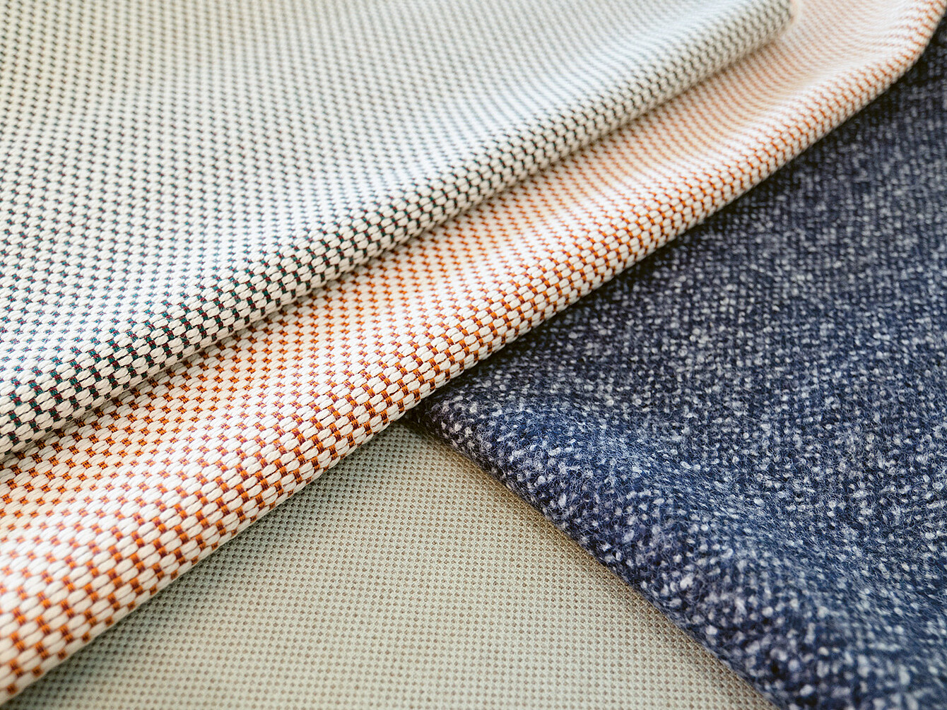 Primo piano di vari campioni di tessuto che mostrano texture e motivi diversi, evidenziando l’importanza della selezione dei materiali nel design. 
