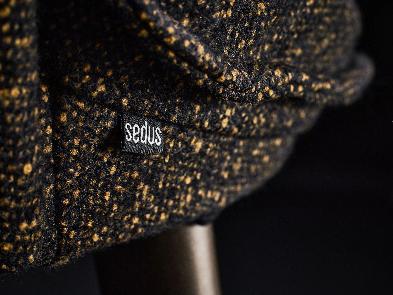 Gros plan sur un revêtement en tissu portant une petite étiquette noire sur laquelle est inscrit « Sedus » en blanc