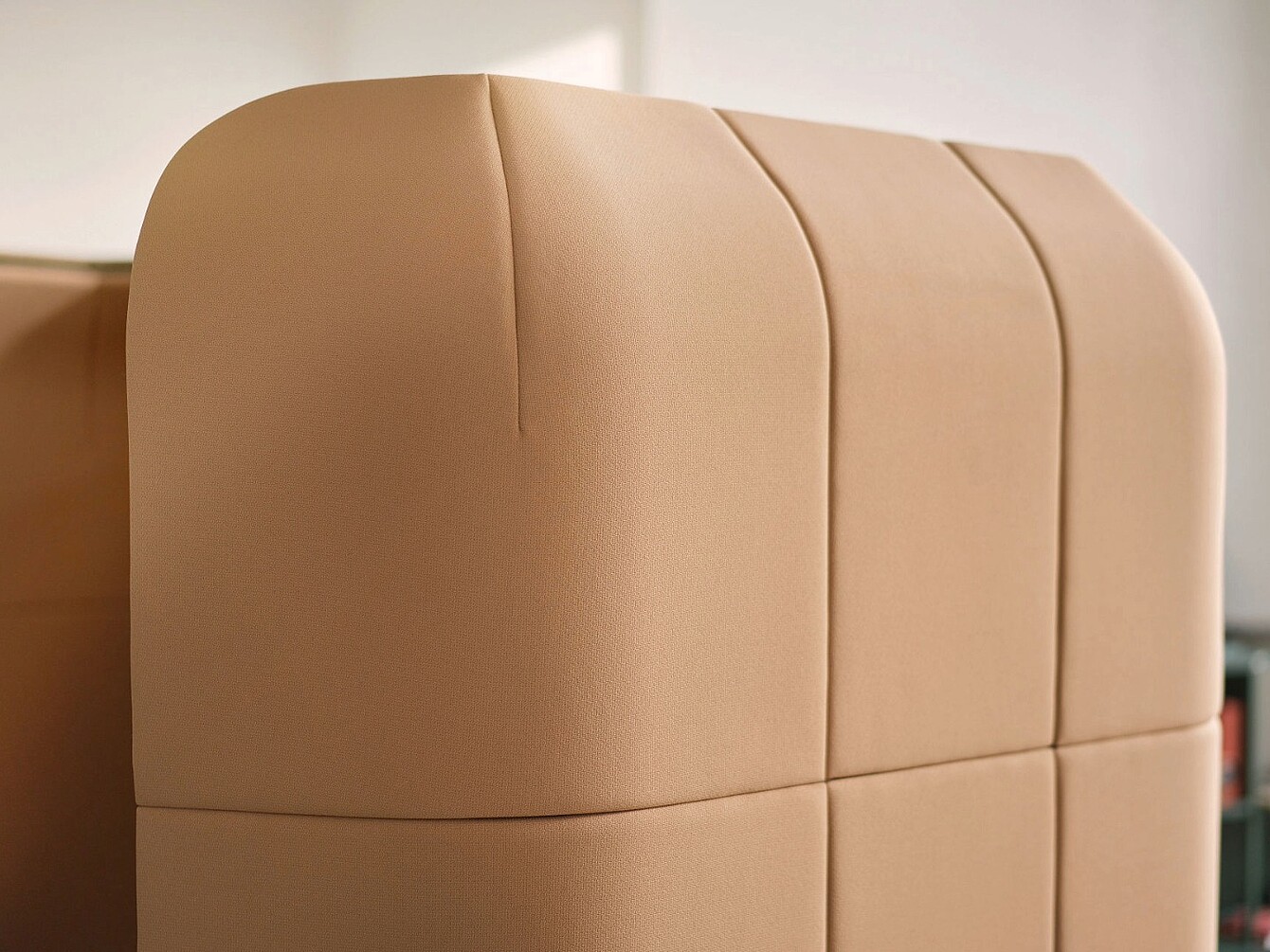 Primo piano di un pannello rivestito in beige con cuciture verticali e orizzontali che formano un motivo a griglia
